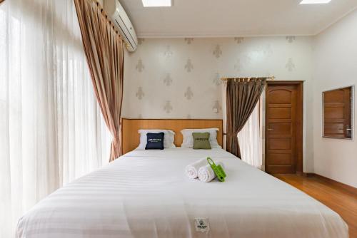 万隆Urbanview Hotel Villa Surya Bandung的卧室配有一张白色大床和两条毛巾