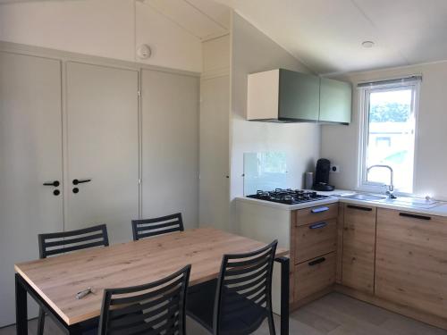Bec-de-MortagneMobile-home Pin的厨房配有木桌、椅子和炉灶。