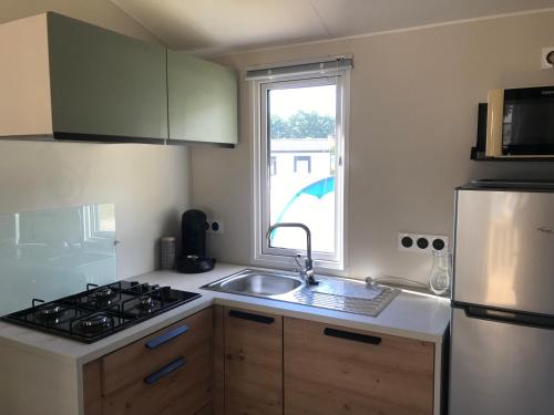 Bec-de-MortagneMobile-home Pin的厨房配有水槽、炉灶和窗户。