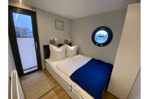 巴特Hausboot Fjord Vela mit Biosauna in Barth的卧室配有蓝色和白色的床和窗户。