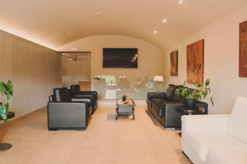 朱内塔斯瓦尔德巴斯酒店的客厅配有黑色皮革家具和平面电视