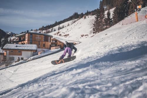 萨尔巴赫Landhaus Saalbach - Joker card included in summer的骑着滑雪板沿着雪覆盖的斜坡滑雪的人