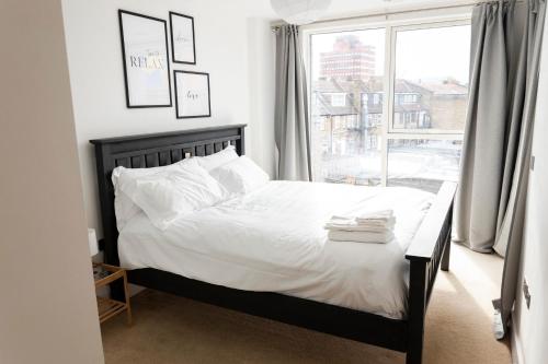 伦敦Modern Brixton Apartment的一间卧室配有一张带白色床单的床和一扇窗户。