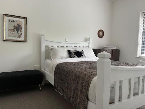 贝尔特比特Contemporary Townhouse Stunning lakeside location的卧室配有白色的床和黑色的搁脚凳