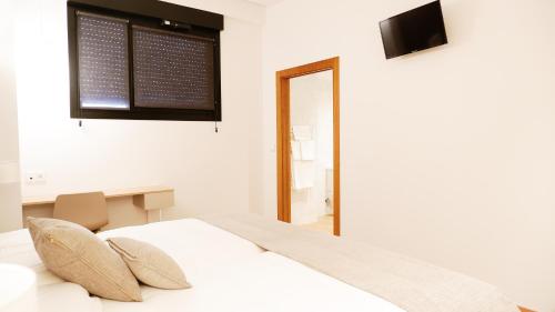 杜兰戈Hotel Ocamiño的一间白色卧室,配有床和电视