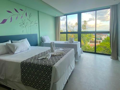嘎林海斯港Pousada Amada Terra的一间卧室设有两张床和大窗户