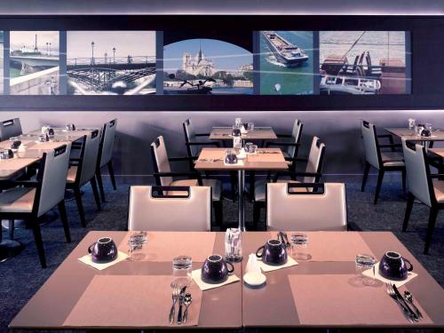 塞纳河畔伊夫里巴黎塞纳河畔伊夫里美居酒店的餐厅设有桌椅,墙上挂有图片