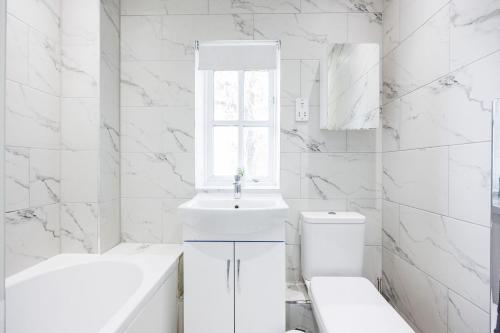 巴尔金Newly refurbished charming 3-Bed House in Barking的白色的浴室设有水槽和卫生间。