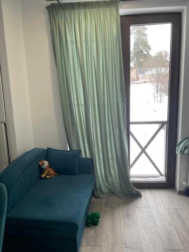 巴库里阿尼Bakuriani mix appartment的坐在窗前蓝色沙发上的泰迪熊