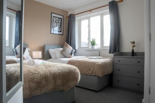 米尔顿凯恩斯Comfortable 4 Bedroom Home in Milton Keynes by HP Accommodation with Free Parking, WiFi & Sky TV的一间卧室配有两张床和镜子