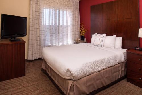 阿尔伯克基Residence Inn by Marriott Albuquerque Airport的一间卧室配有一张大床和一台平面电视