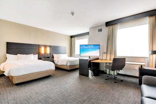 科珀斯克里斯蒂Residence Inn by Marriott Corpus Christi Downtown的酒店客房设有两张床、一张桌子和一台电视。