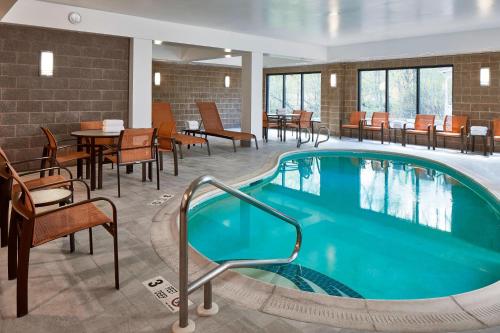 奥尔巴尼Fairfield Inn & Suites by Marriott Albany Airport的游泳池位于酒店带桌椅的客房内