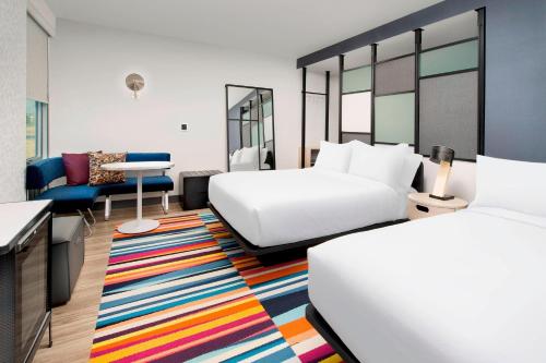 威尔明顿Aloft Wilmington at Coastline Center的酒店客房带两张床,还有色彩缤纷的地毯。