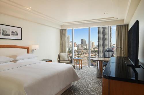 马尼拉Sheraton Manila Bay的酒店客房设有一张床和一个大窗户