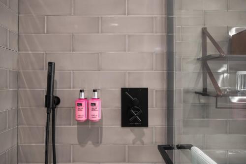 纽约Moxy NYC Downtown的浴室内提供2瓶粉红色洗发水和淋浴