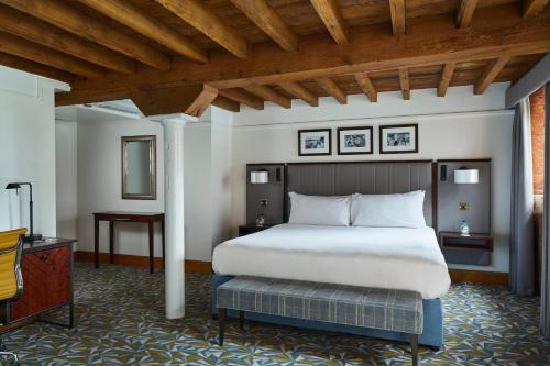 曼彻斯特万豪曼切斯特维多利亚&艾伯特酒店的一间卧室设有一张大床和木制天花板