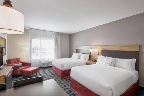 梅迪辛哈特TownePlace Suites by Marriott Medicine Hat的酒店客房,配有两张床和椅子