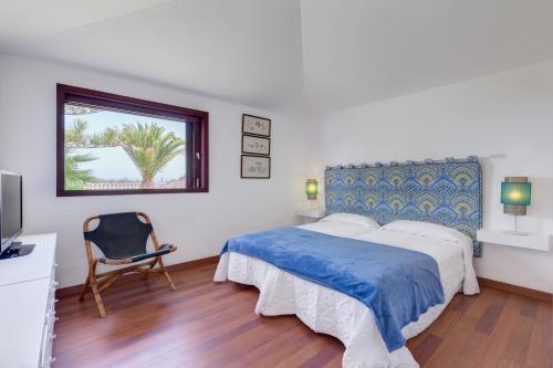 滨海帕尔姆Chalet Umbelina con jardin y vista al mar的卧室配有床、椅子和窗户。