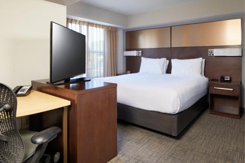 卡尔斯巴德圣地亚哥卡尔斯巴德公寓式酒店的酒店客房配有一张床和一张书桌及一台电视
