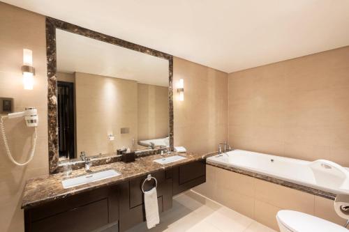 吉赞吉赞万怡酒店的浴室配有2个盥洗盆、浴缸和大镜子