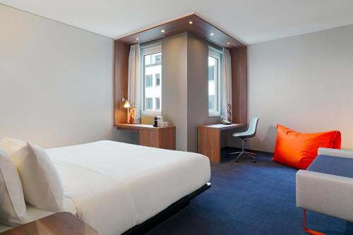 慕尼黑慕尼黑雅乐轩酒店的一间酒店客房,配有一张白色的床和一张书桌