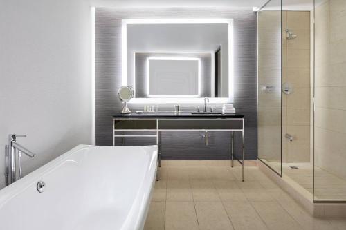多瓦尔Marriott Montreal Airport In-Terminal Hotel的浴室配有盥洗盆、镜子和浴缸