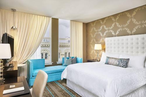 波特兰波特兰奈士豪华精选酒店的一间卧室配有一张床、一把蓝椅和一个窗户。