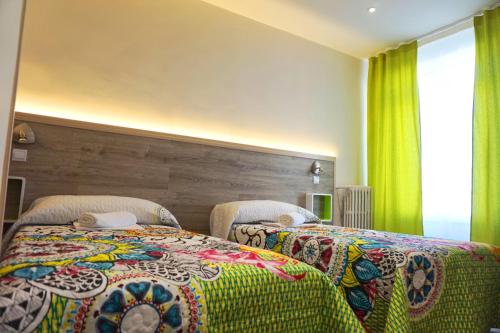 马德里马德里穆乔旅舍的一间卧室配有两张带彩色毯子和窗户的床。