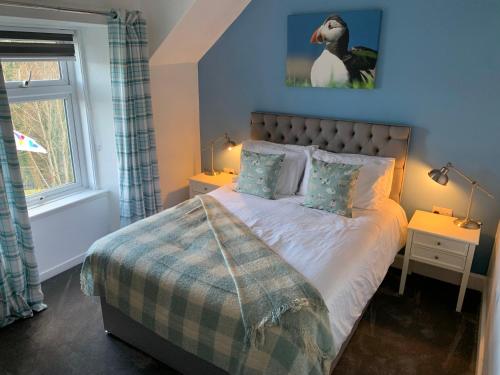 托伯莫里Burnbank BnB的卧室配有一张挂着企鹅照片的床