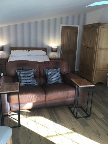 Rhuddlan花园套房公寓的卧室里一张棕色的皮沙发,配有床