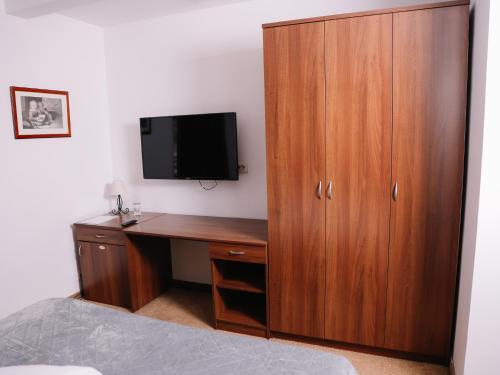 巴尼亚卢卡Stara Ada Banja Luka的一间卧室配有书桌、电视和木制橱柜