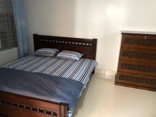 吉大港Home Away From Home的一间卧室配有带2个枕头和梳妆台的床