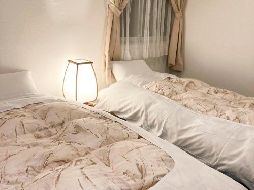 热海Pension Todoroki的卧室内的一张未铺好的床,配有灯