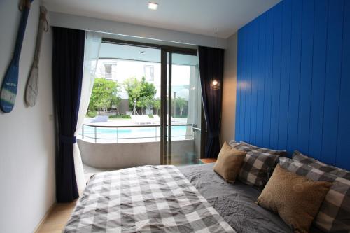 佛丕บ้านแสนคราม หัวหิน Family Room - Pool Access ห้องติดสระ的一间卧室设有蓝色的墙壁、一张床和一个窗户。