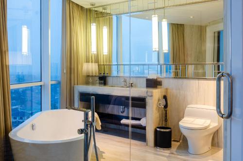 泗水Hotel Ciputra World Surabaya managed by Swiss-Belhotel International的带浴缸和卫生间的浴室。