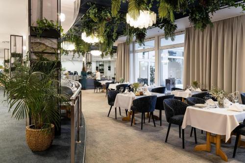 加茨比亚格拉阿斯特酒店 的一间设有白色桌椅的餐厅,种植了植物