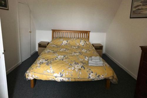 CreagorryTraditional Croft house的一张黄色棉被床,上面有毛巾