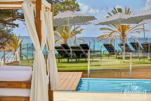 帕格拉Secrets Mallorca Villamil Resort & Spa - Adults Only (+18)的毗邻度假酒店的带椅子和遮阳伞的游泳池