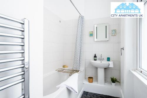 伦敦Charming 1 Bed Apt in Kensington - Free London Tour Included By City Apartments UK Short Lets Serviced Accommodation的白色的浴室设有水槽和浴缸。