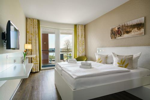 瓦伦Radlon Fahrrad-Komfort-Hotel的酒店客房设有一张白色大床和一个窗户。
