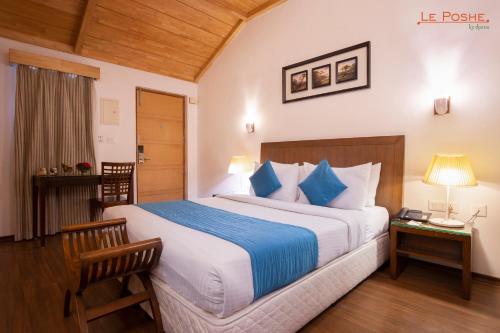 科代卡纳尔Le Poshe, Kodaikanal的一间卧室配有一张带蓝白色枕头的大床