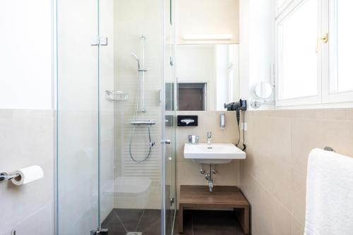 克拉根福Select Hotel Moser Verdino Klagenfurt的一间带玻璃淋浴和水槽的浴室