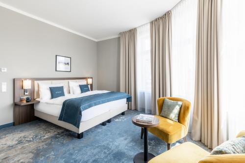 克拉根福Select Hotel Moser Verdino Klagenfurt的配有一张床和一把椅子的酒店客房