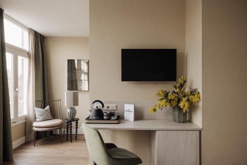 阿姆斯特丹Adam Suites Hotel的客厅配有一张桌子,墙上配有电视