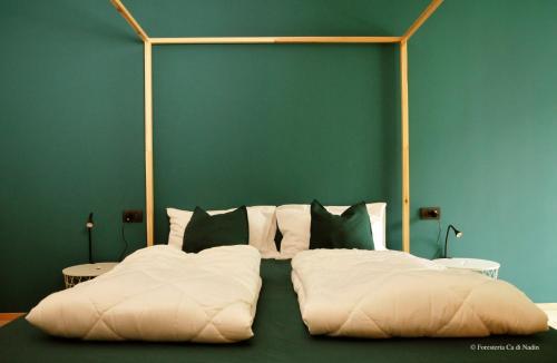 CarriolaForesteria Cà di Nadin的一张带白色枕头和绿色墙壁的床