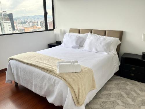 基多Suite amoblada con aparcamiento privado excelente vista y ubicación! Sector La Carolina的卧室配有白色的床和大窗户