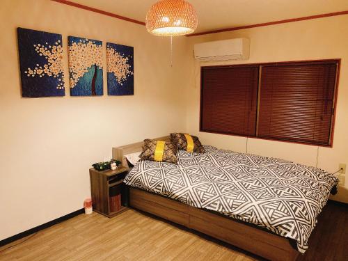 大阪悠雅軒的卧室配有一张床,墙上挂有绘画作品