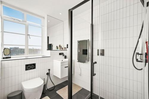 伦敦Two Bedroom Flat in Kensington的带淋浴和卫生间的白色浴室