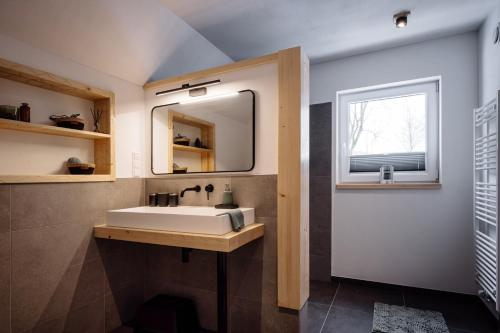 比特亨巴赫Urlaub am Schwarzbach mit Sauna und Whilpool的一间带水槽和镜子的浴室以及窗户。